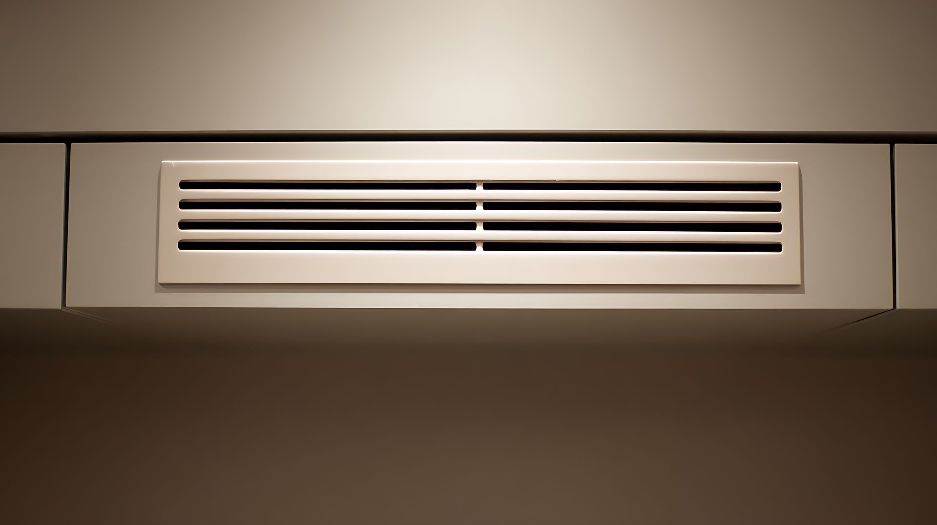 Grille d'aération rectangulaire à lamelles horizontales intégrée dans un mur.