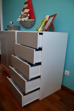 Uma cómoda com quatro gavetas numa sala com uma parede azul.