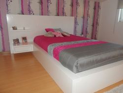 Uma cama com um cobertor rosa e cinza 