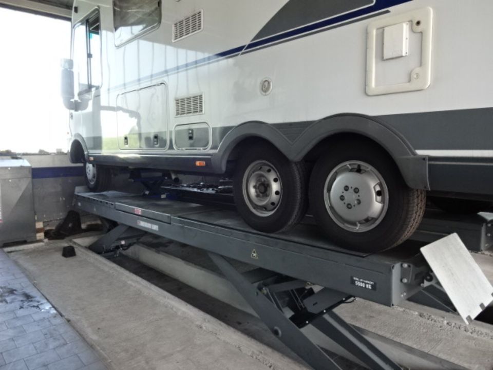Weißes Wohnmobile in der Werkstatt auf einem Wagenheber.