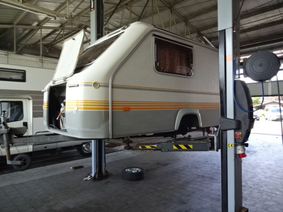 Wohnwagenanhänger auf einer Hebebühne in der Werkstatt von Autohaus Raithel/