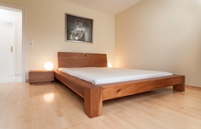 Ein Schlafzimmer mit einem Holzbett und einem Bild an der Wand darüber.