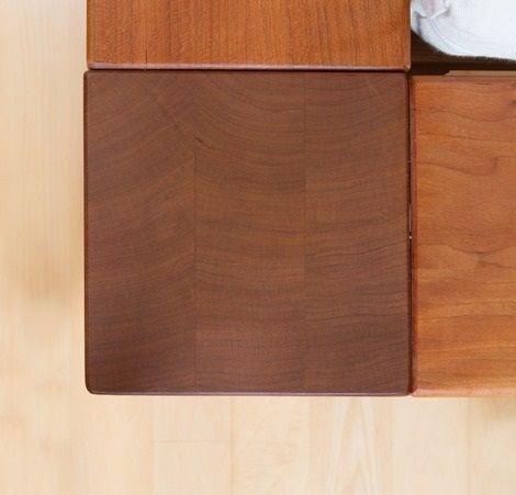 Ein Holztisch steht auf einem Holzboden neben einem Bett.