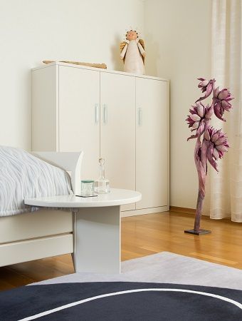 Ein Schlafzimmer mit einem Bett, einem Tisch, einer Vase und einer Statue.