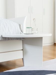 Ein weißer Couchtisch in einem Wohnzimmer neben einem Bett.