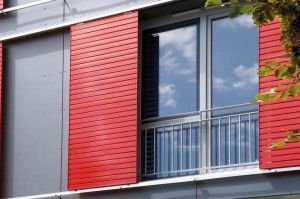 Ein Gebäude mit roten Schiebefenstern und einem Balkon.