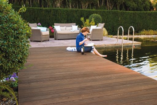 Ein Mann sitzt auf einem Holzdeck neben einem Teich.