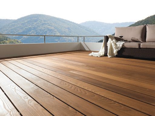 Eine Holzterrasse mit einer Couch und Bergen im Hintergrund