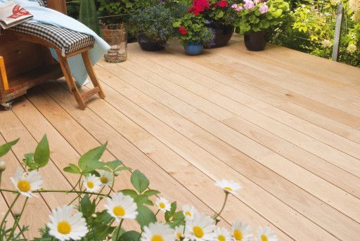 Ein Holzdeck mit Blumen und einem Stuhl darauf.