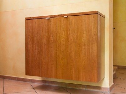In einem Zimmer hängt an einer Wand ein Holzschrank.