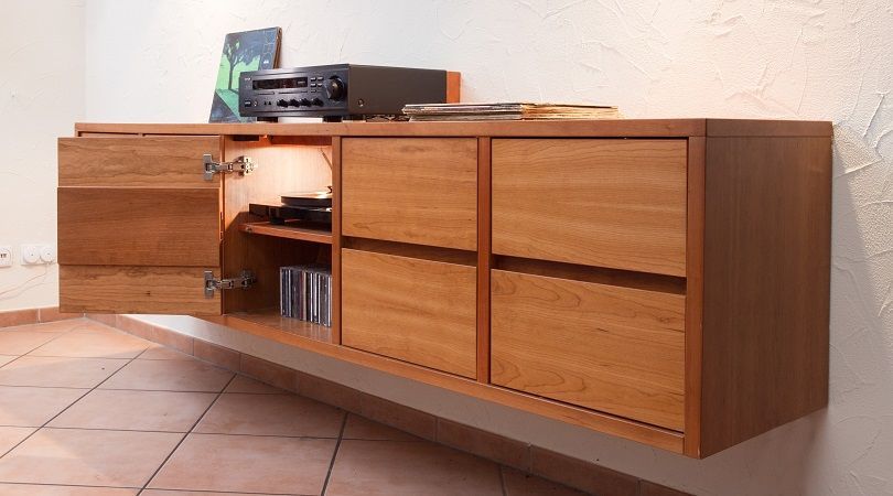 An einer Wand hängt ein Holzschrank mit Schubladen.