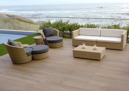 Eine Terrasse mit Sofa, Stühlen und Tisch mit Blick auf das Meer
