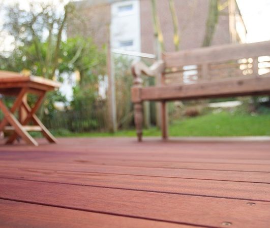 Eine Holzterrasse mit einer Bank und einem Tisch im Hintergrund.