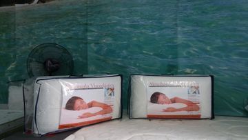 Hay dos almohadas encima de una cama al lado de un ventilador.