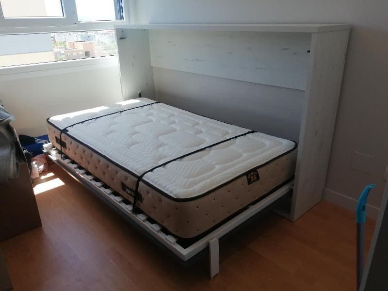 Una cama con un colchón y una ventana al fondo.