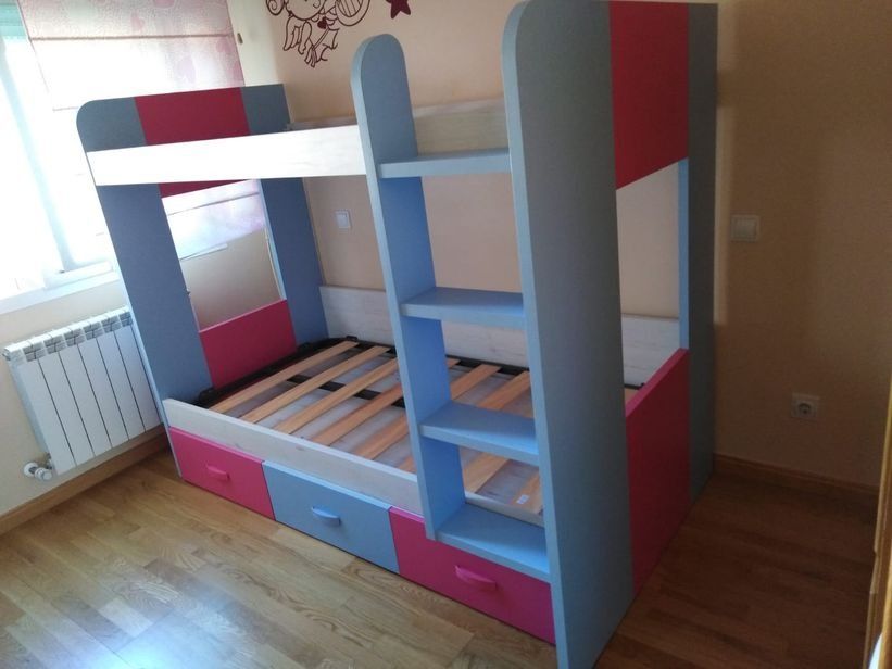 Una litera con escaleras y cajones en un dormitorio.