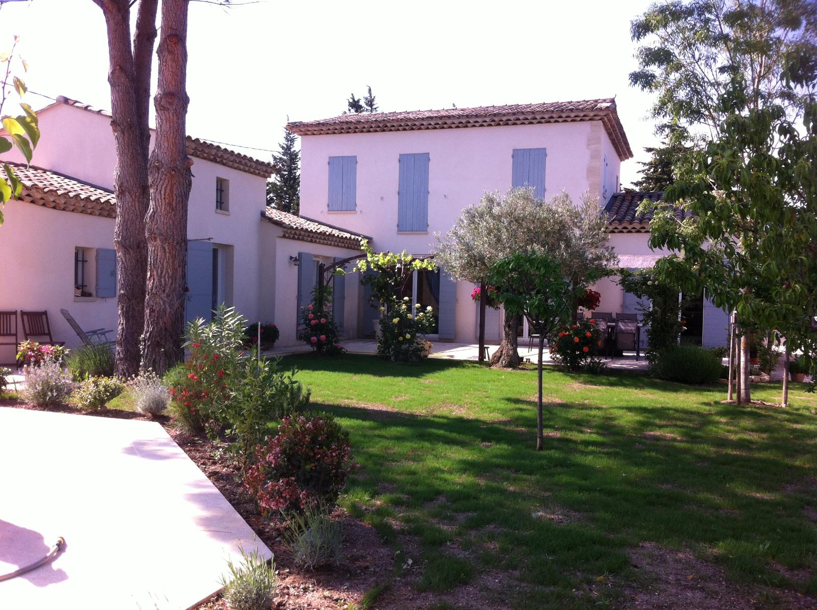 Cour ensoleillée avec maisons en stuc à deux étages, pelouse verte et palmiers