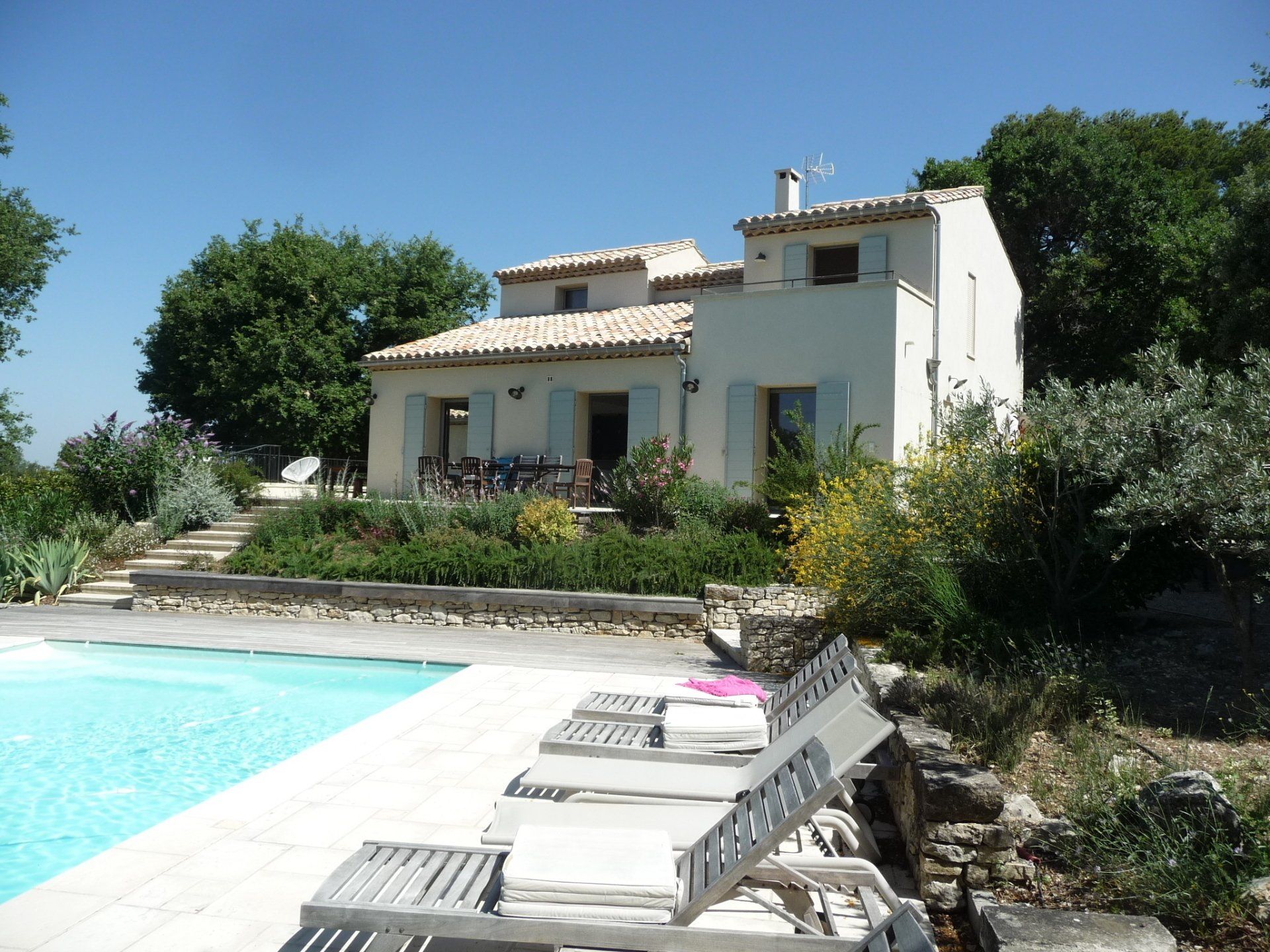 Villa avec piscine, chaises longues et jardin sous un ciel ensoleillé
