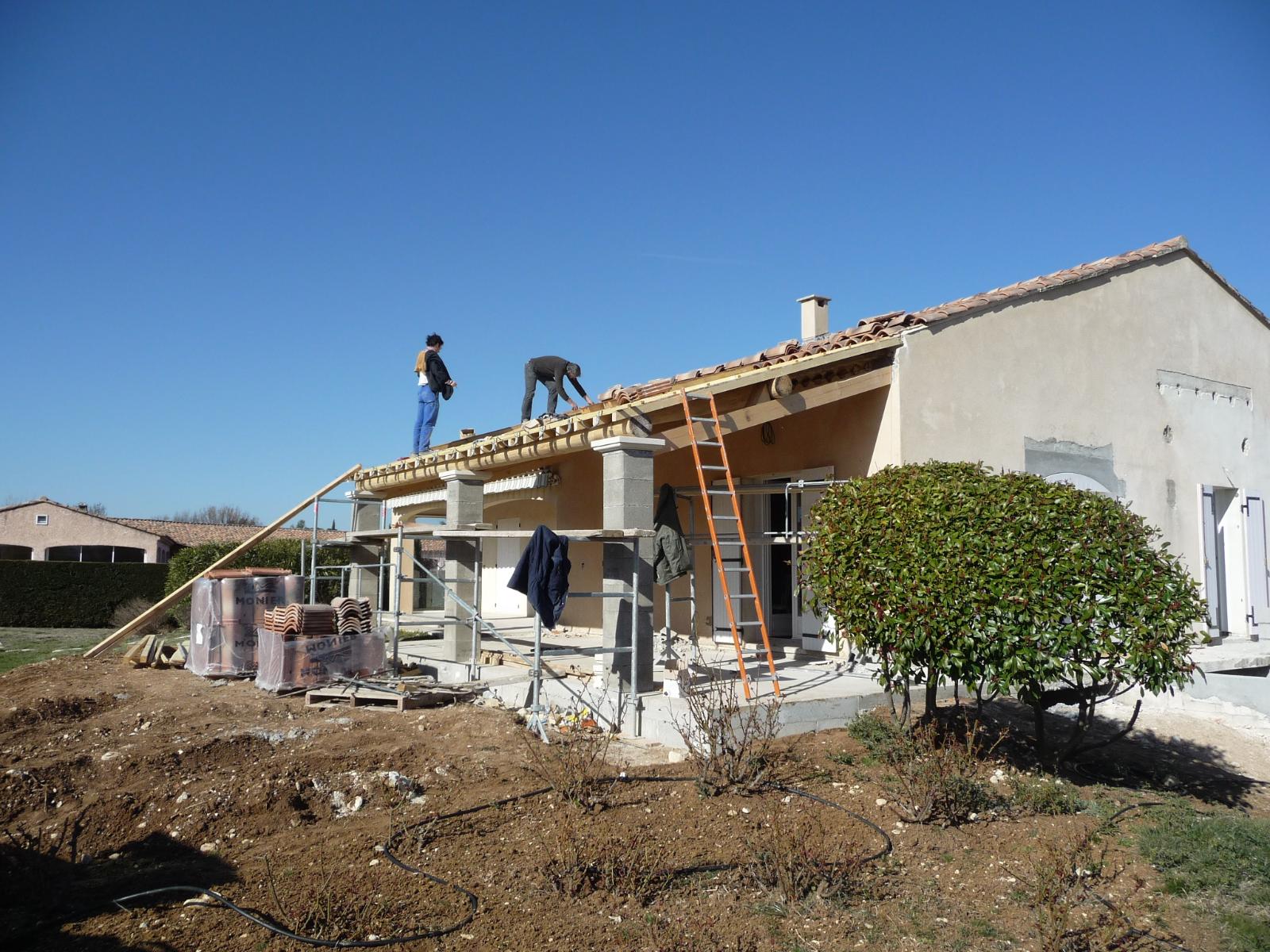 Des ouvriers sur des échafaudages réparent le toit d'une maison sous un ciel bleu dégagé