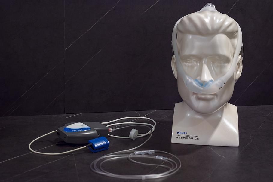 Une tête de mannequin portant une canule nasale avec un concentrateur d'oxygène sur une table.