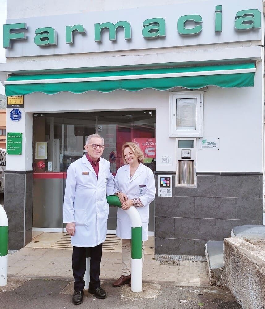 Un hombre y una mujer de pie frente a una farmacia.