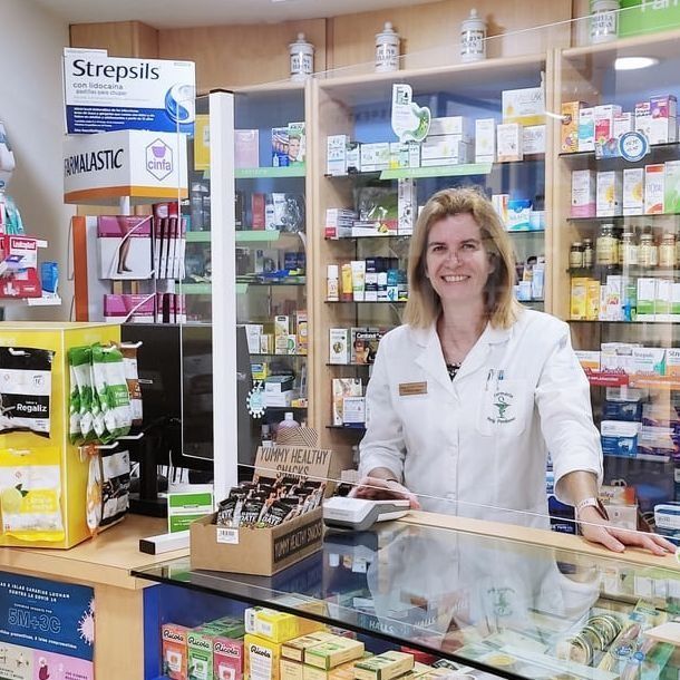 Una mujer está parada detrás de un mostrador en una farmacia.