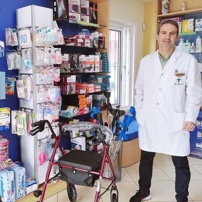 Un hombre con bata de laboratorio está junto a un andador en una tienda.