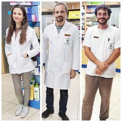 Tres personas con batas blancas están de pie en una farmacia.