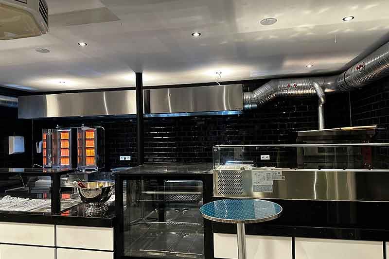 Restaurantinnenraum mit Serviertheke und kleinem Tisch. Schwarz-weißes Dekor, Ziegelwand und Fliesenboden.