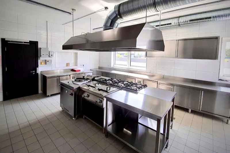 Großküche mit Geräten aus Edelstahl und Dunstabzugshaube.