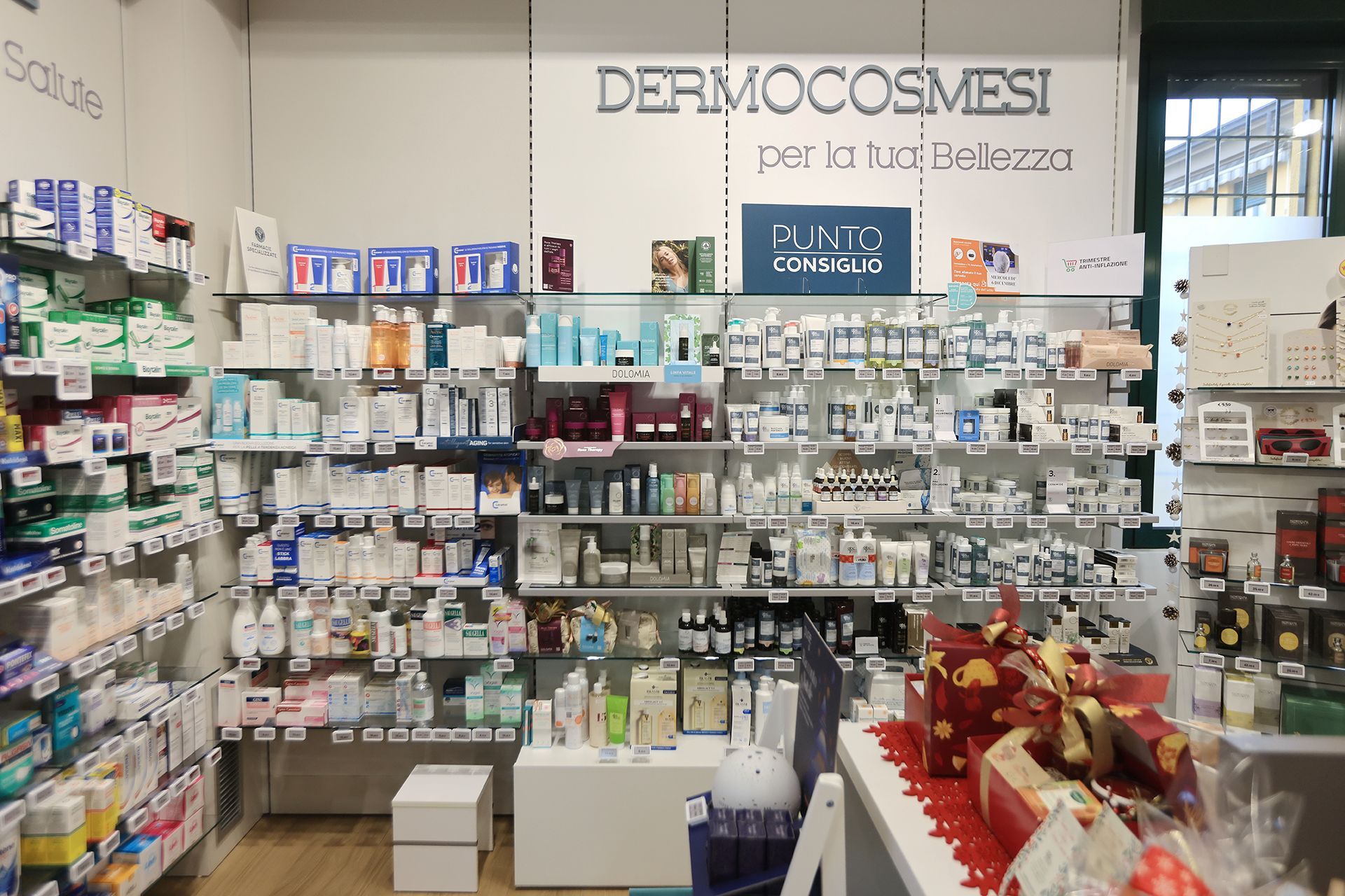 Scaffali di prodotti per la cura della pelle e cosmetici in una farmacia, con un banner che recita 