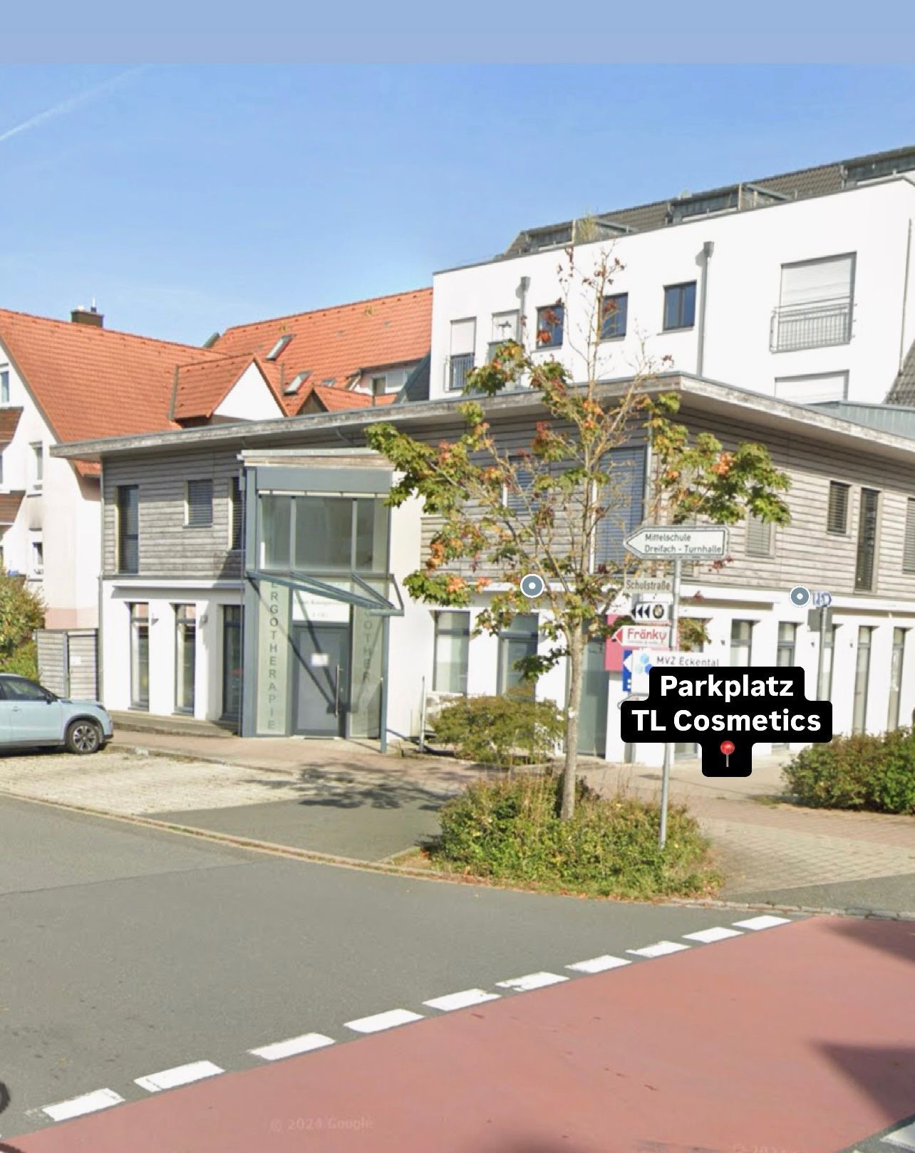 Vor einem Gebäude mit einem Schild mit der Aufschrift „Parkplatz TL Cosmetics“ parkt ein Auto.