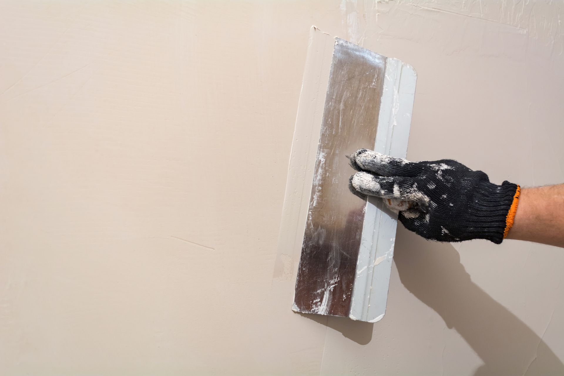 Eine Person verputzt eine Wand mit einer Kelle.