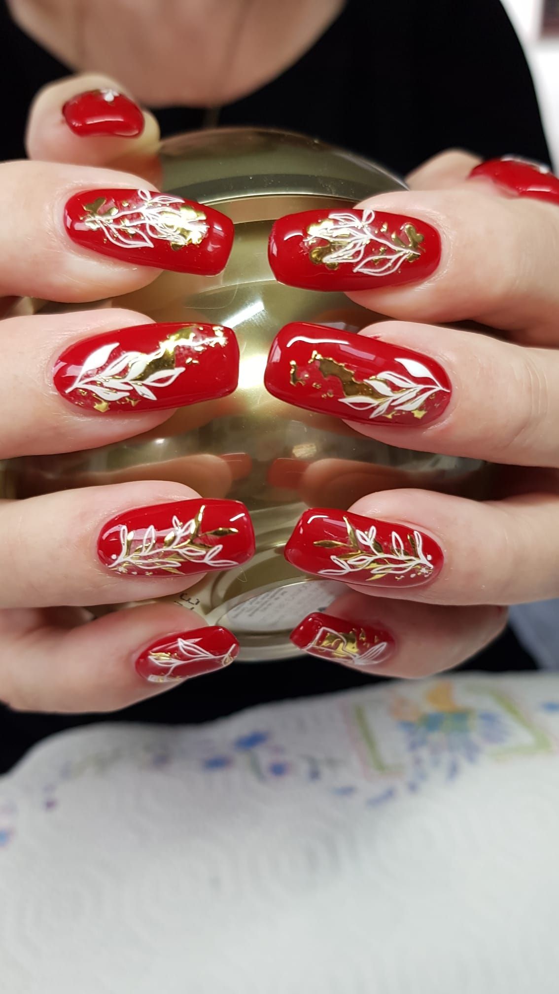 Hand mit rosafarbenem Nageldesign, die gelbe Narzissen hält.