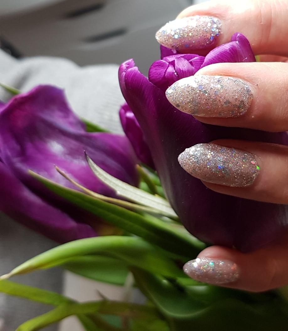 Rote Fingernägel mit goldenen Blumenmustern, die eine goldene Glaskugel halten.