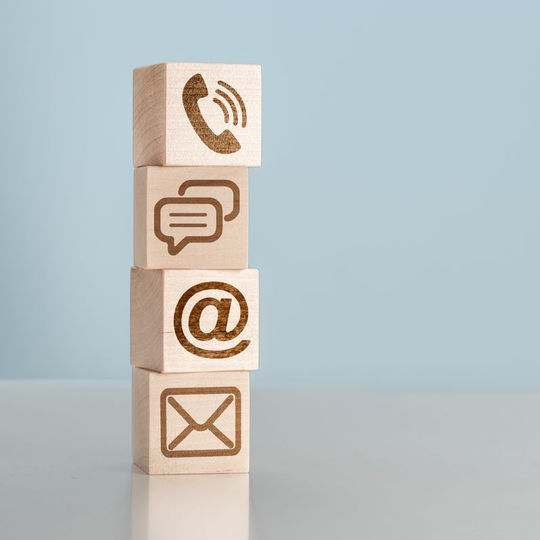 Blocs en bois empilés avec des icônes de communication gravées.