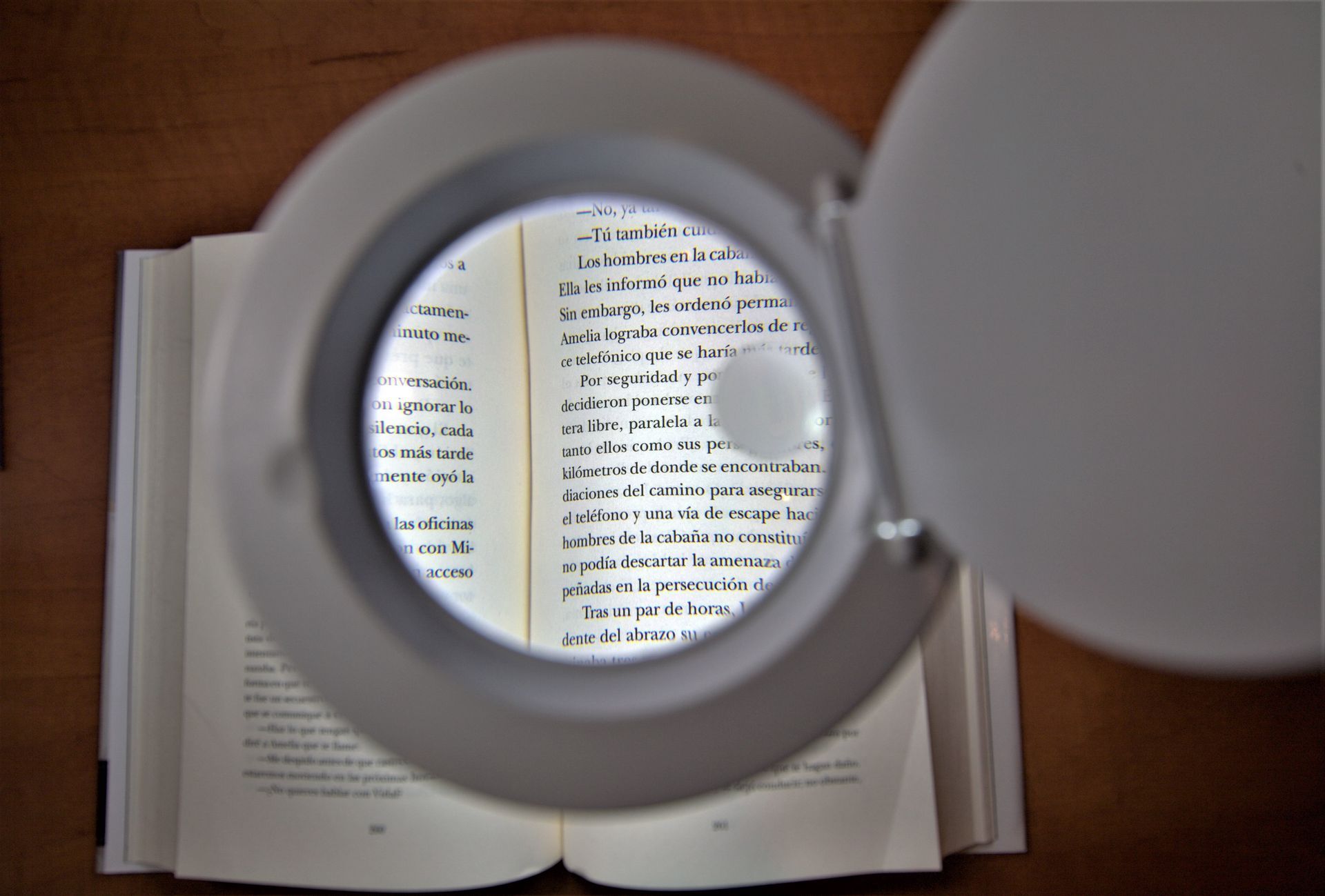 Libro abierto visto a través de una lupa sobre una mesa de madera