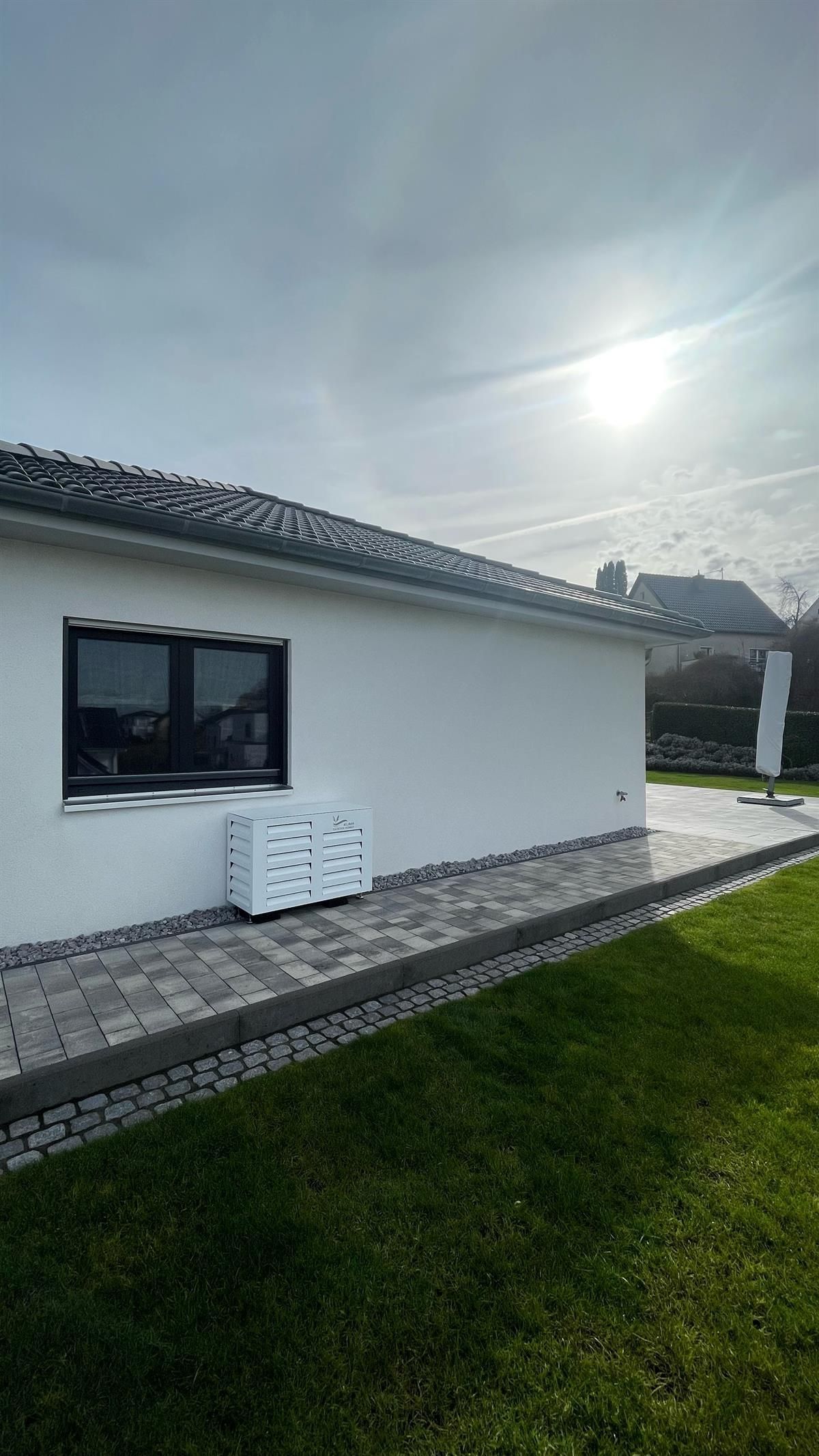 Ein weißes Haus mit einer Terrasse und einer Wiese davor.