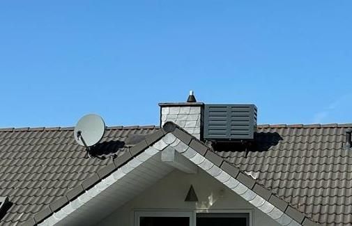 Ein Dach mit einem Schornstein und einer Satellitenschüssel darauf.
