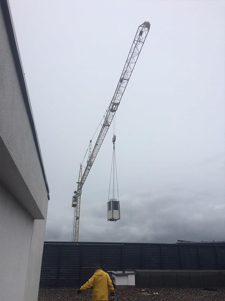 Ein Mann in einer gelben Jacke steht vor einem Kran