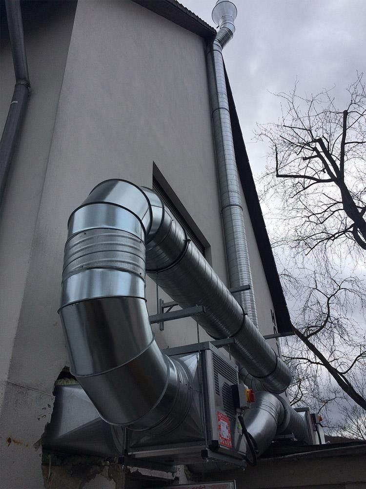 An der Seite eines Gebäudes ist ein großes Metallrohr angebracht.