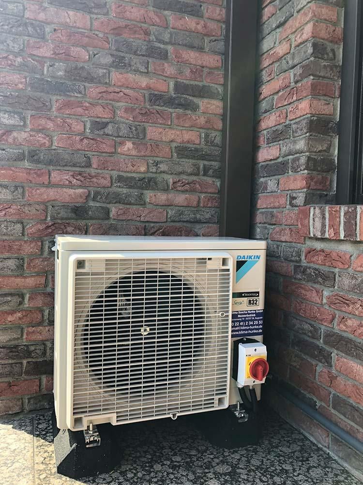 An der Seite eines Backsteingebäudes steht eine Klimaanlage.