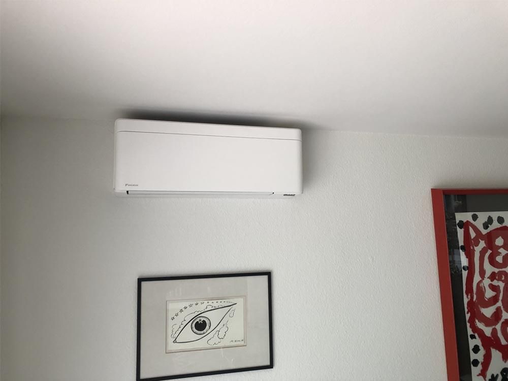 An einer Wand neben einer an der Wand montierten Klimaanlage hängt das Bild eines Auges.
