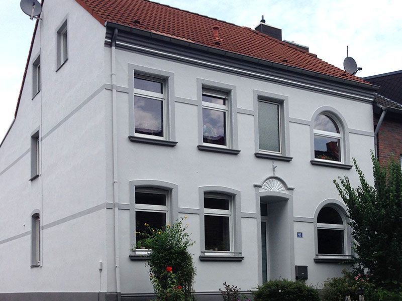 Ein weißes Haus mit Bogenfenstern und einem roten Dach