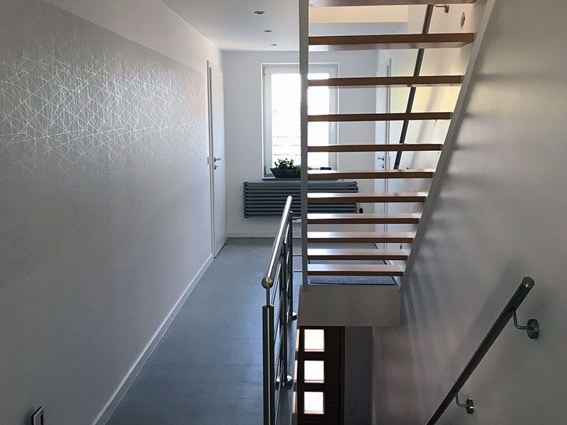 Ein Flur mit einer Holztreppe, die in den zweiten Stock führt
