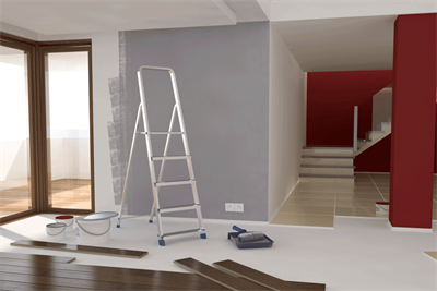 Ein Raum mit einer Leiter und einem Eimer Farbe auf dem Boden.