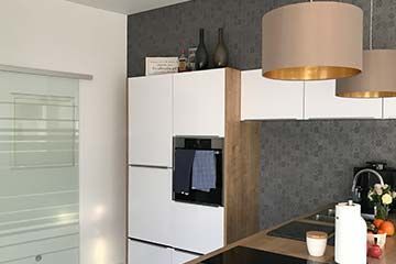 Eine Küche mit weißen Schränken, einem Herd, einem Kühlschrank und einer Mikrowelle.