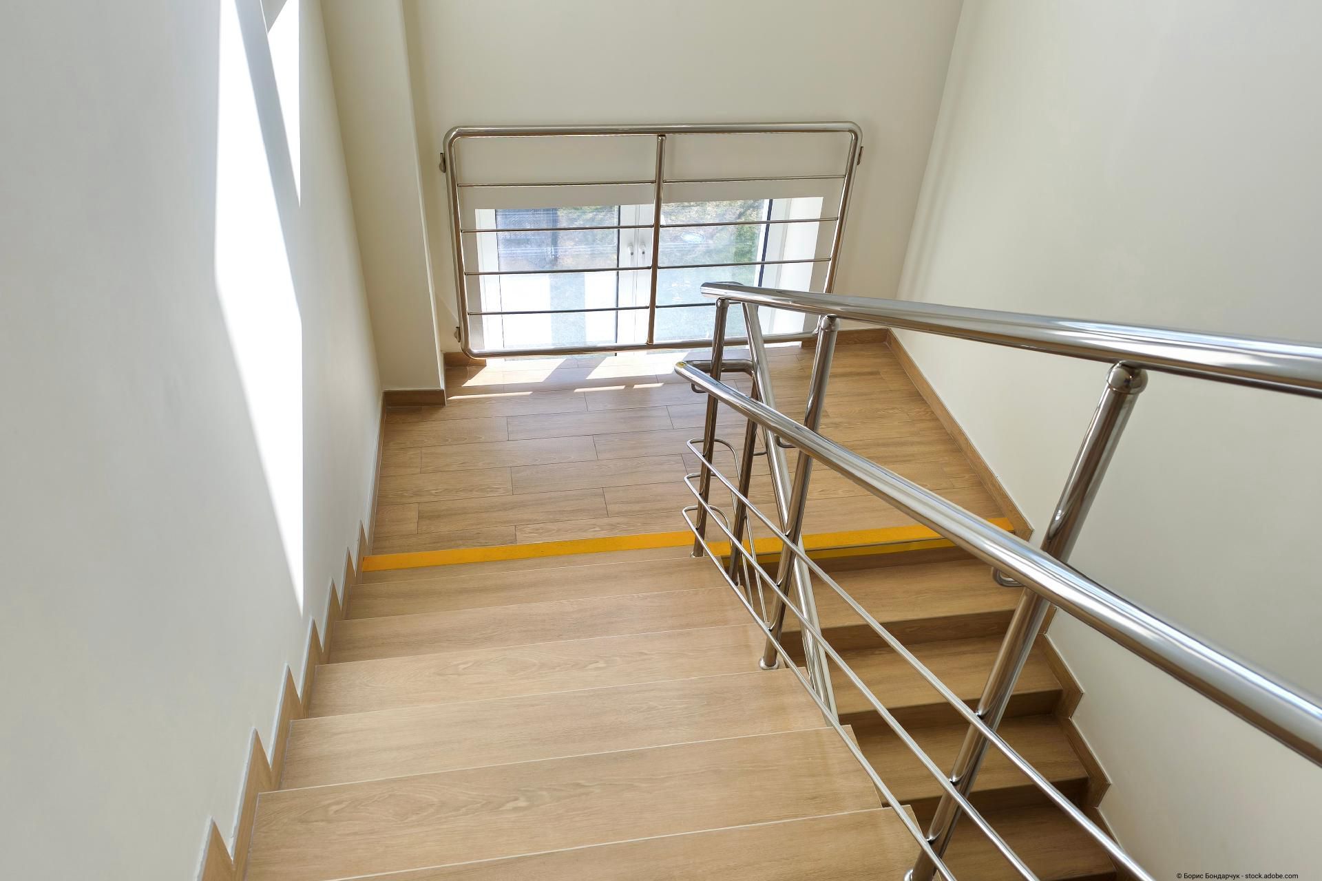 Moderner Glasbalkon mit Edelstahlbefestigungen an einer Hausfassade vor klarem blauen Himmel.