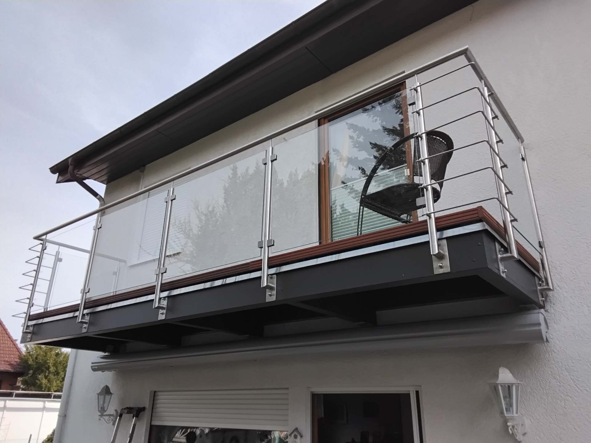 Moderner Balkon mit Glasfüllung und Edelstahlpfosten an Wohnhausfassade