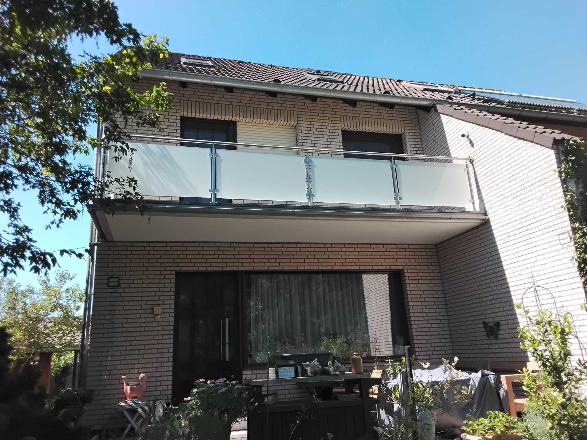 Großer Balkon mit Glasgeländer über Terrasse eines Einfamilienhauses
